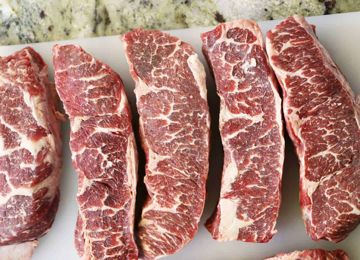 Raw boneless short ribs on a cutting board. 