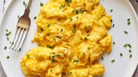 Fluffy scrambled eggs served on a plate with a fork.