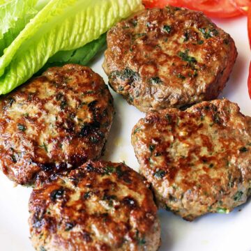 Turkey burgers served with lettuce and sliced tomatoes.