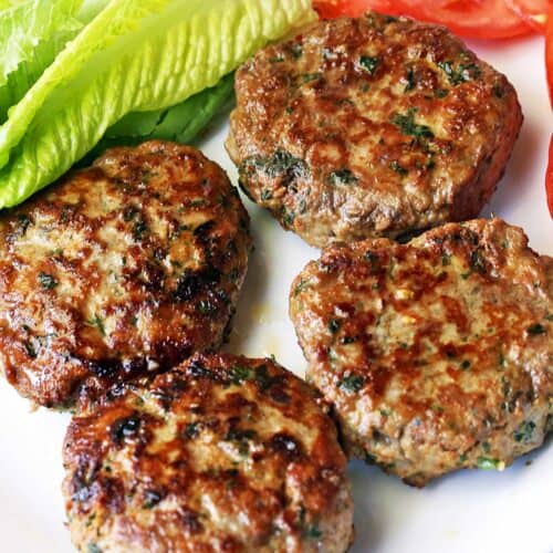 Turkey burgers served with lettuce and sliced tomatoes.