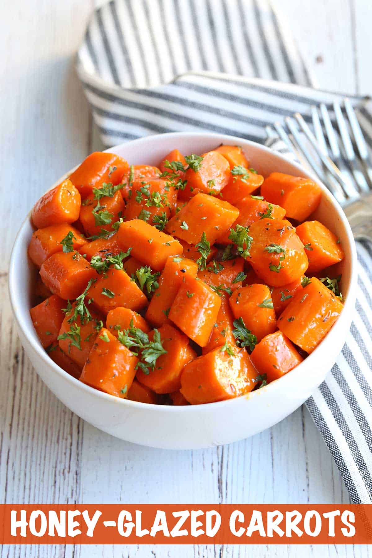 Honey-glazed carrots served in a white bowl with forks. 