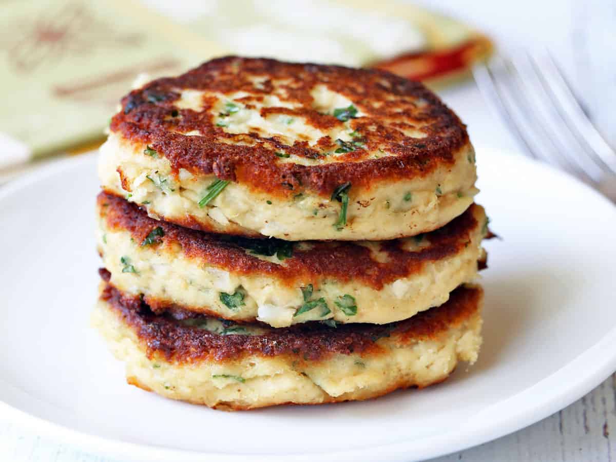 Three leftover turkey patties stacked on a white plate. 