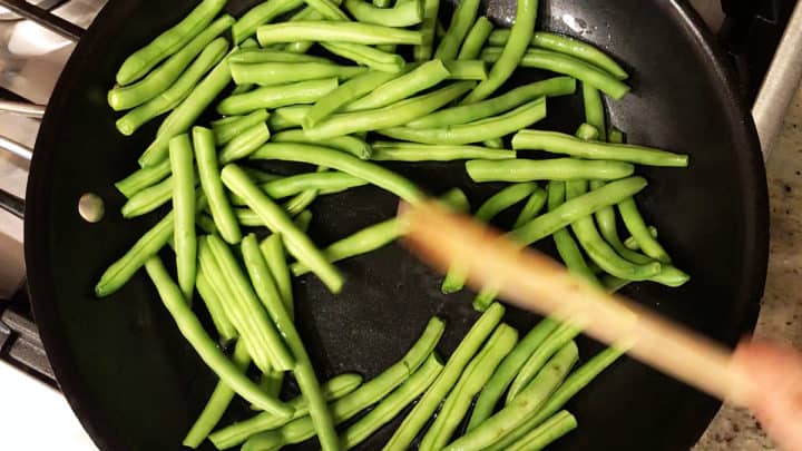 Cooking the green beans in the skillet.