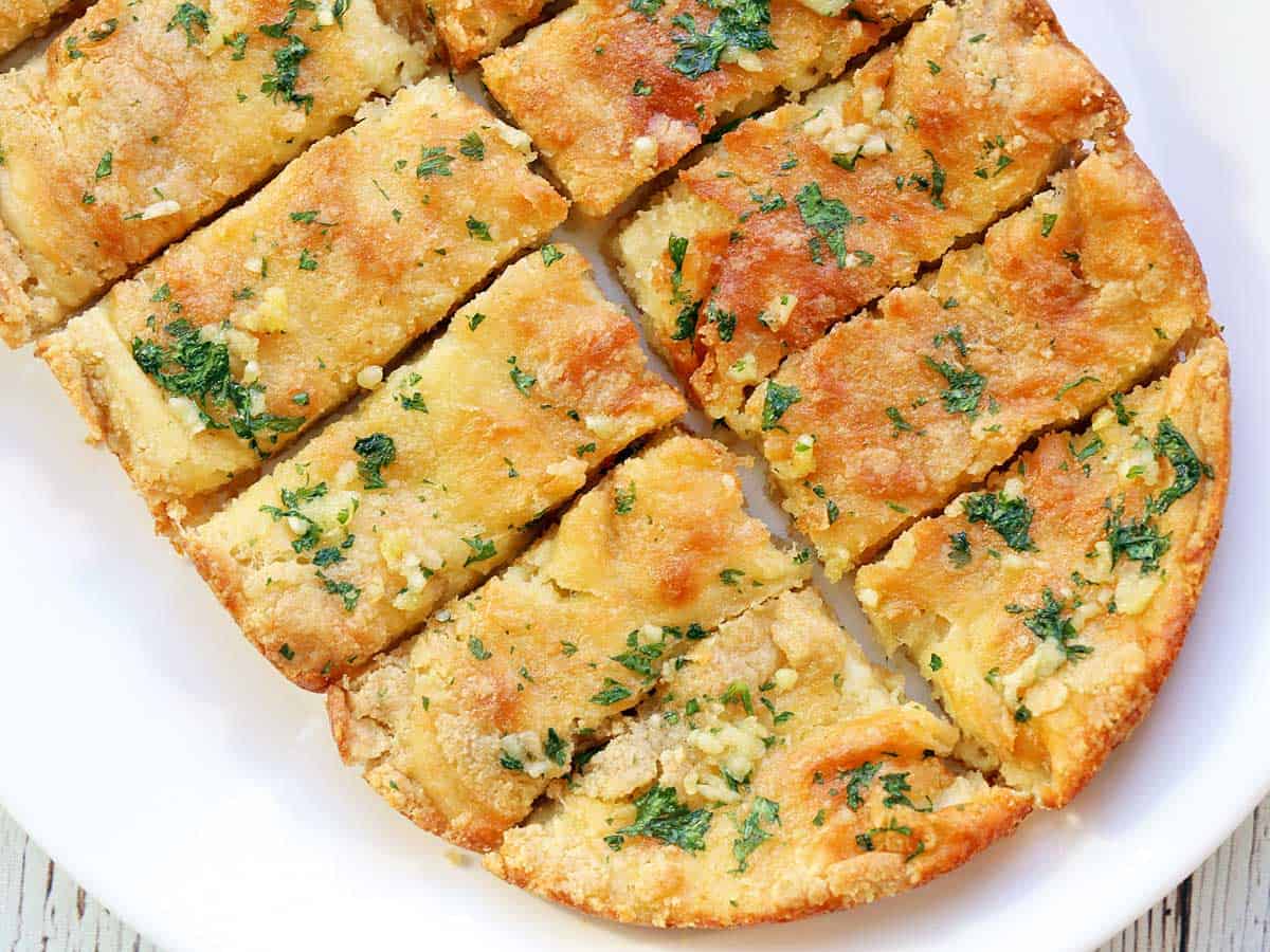 Keto garlic bread is served on a white platter. 