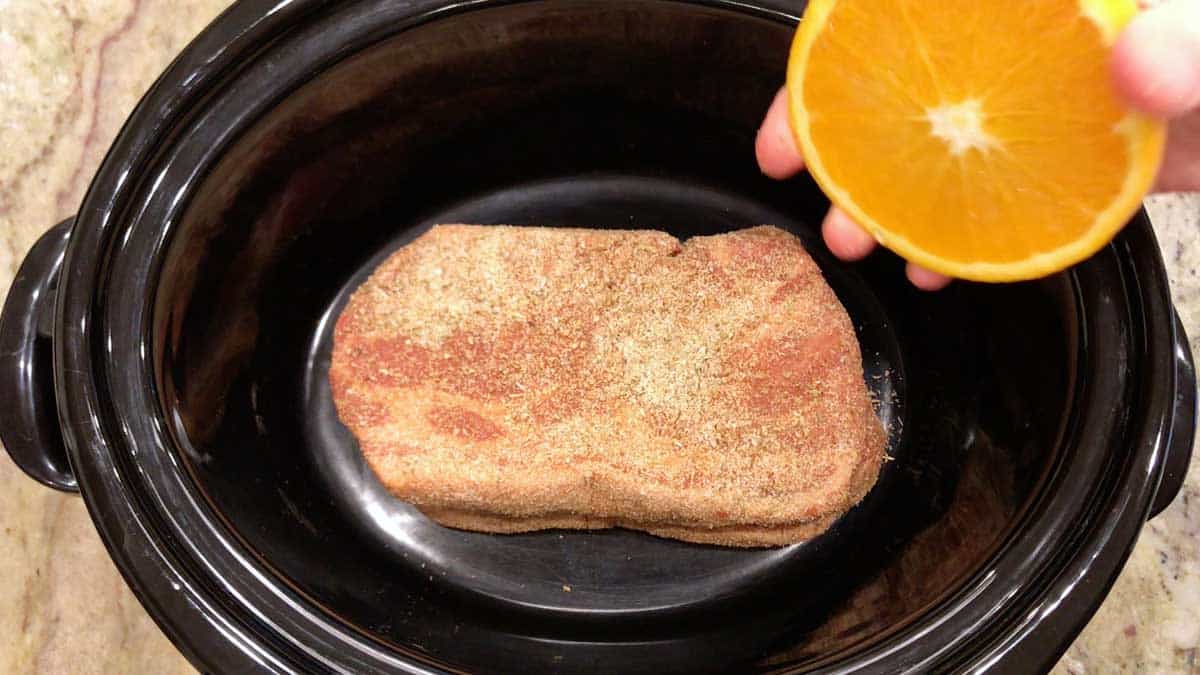 Place the pork in the slow cooker and squeeze orange juice on top. 
