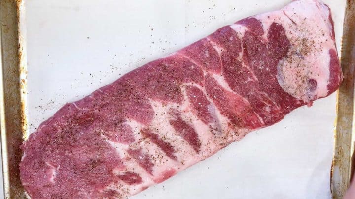 Raw spare ribs on a baking sheet.