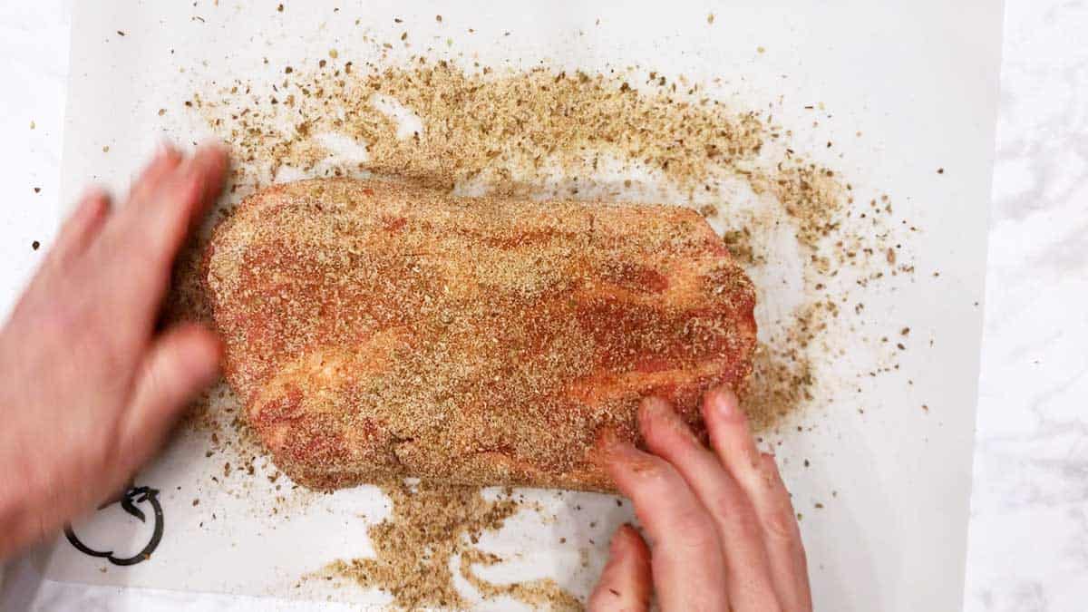 Coating a pork shoulder with spices. 