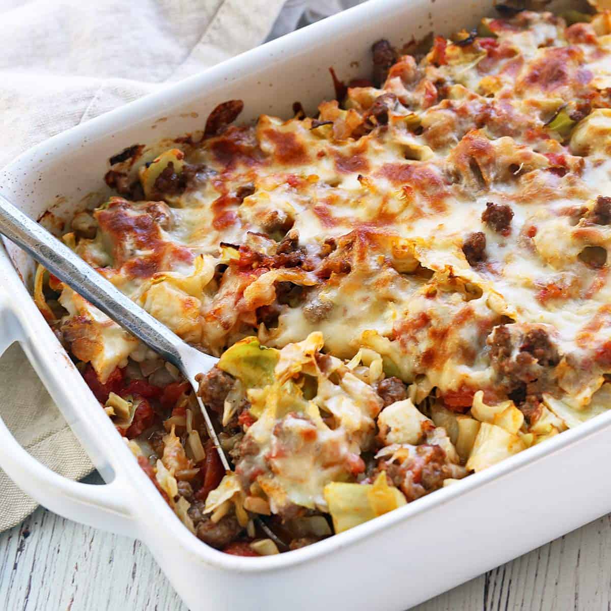 Cabbage casserole served in a white baking dish with a serving spoon.