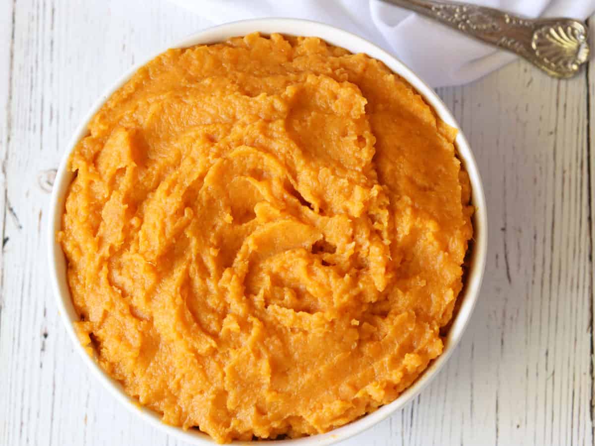 Mashed sweet potatoes served in a white bowl. 