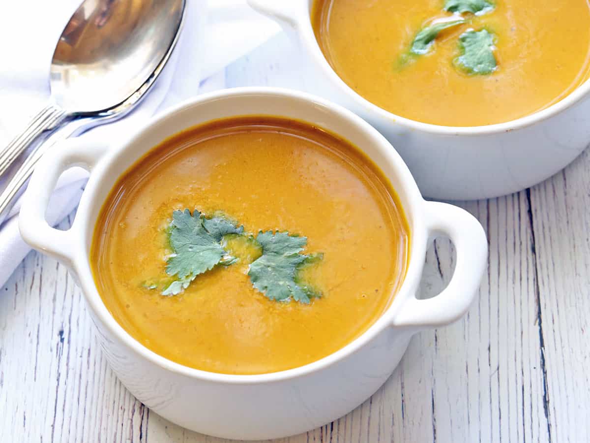 Pumpkin curry soup served in white bowls. 