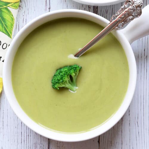 Cream of broccoli soup served in a white bowl with a spoon.