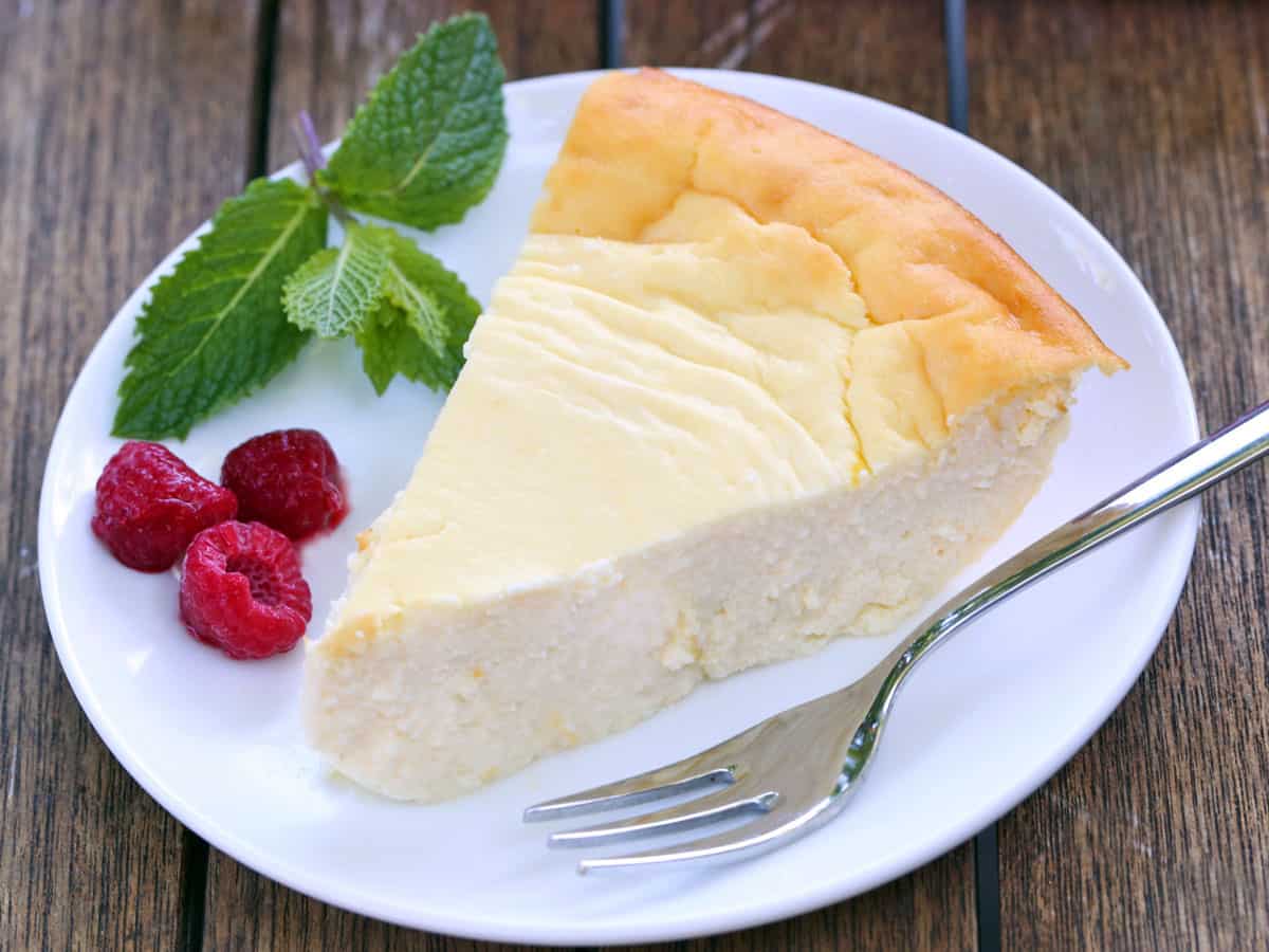 Pastel de queso ricotta servido en un plato blanco con bayas. 