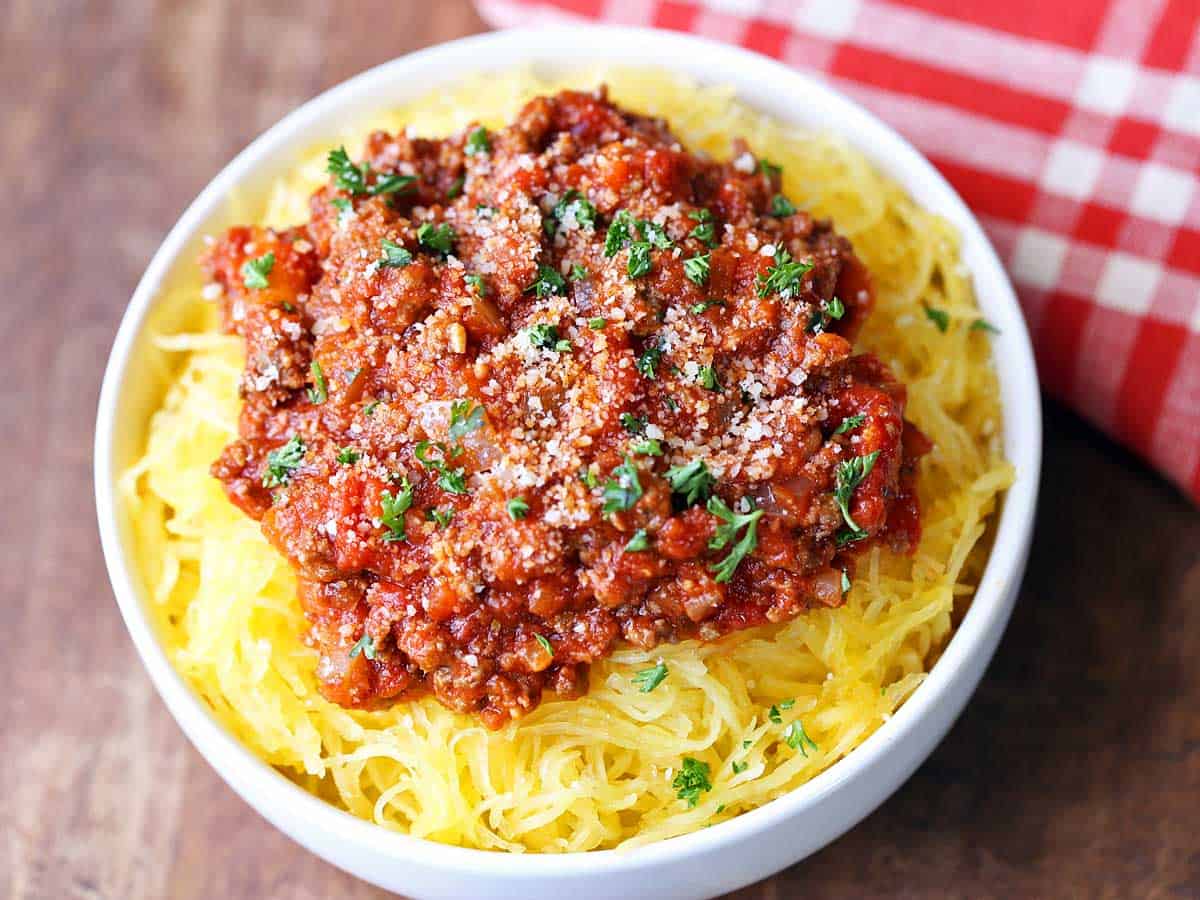 Spaghetti squash served in a white bowl, topped with meat sauce. 