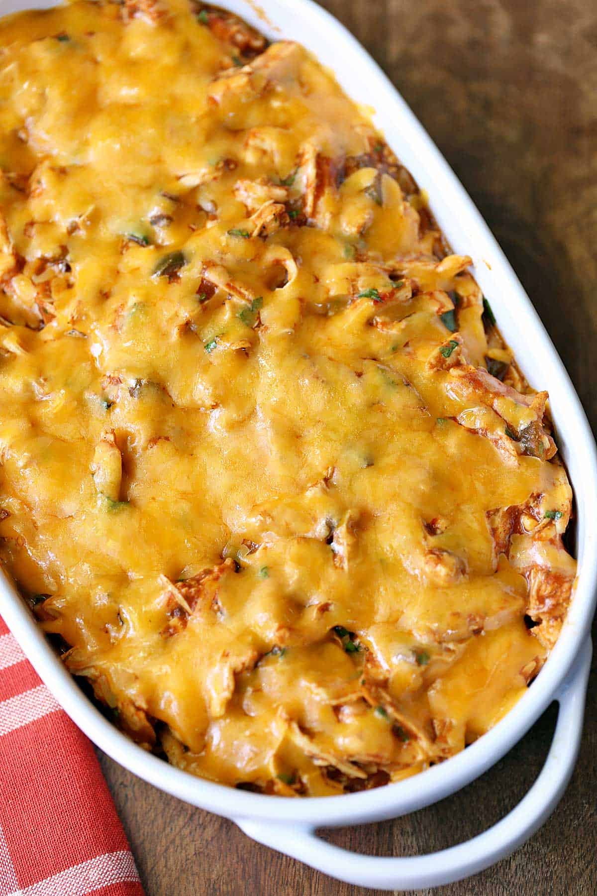 Chicken enchilada casserole served in a white baking dish with a red napkin. 