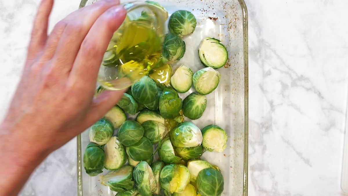 Adding olive oil to Brussels sprouts. 