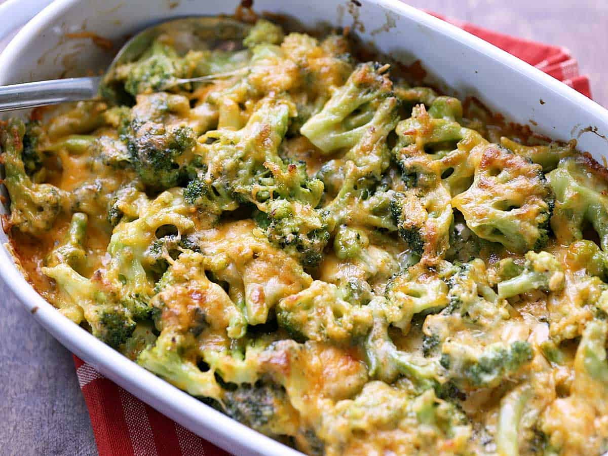 Broccoli cheese casserole served in a white baking dish with a spoon. 