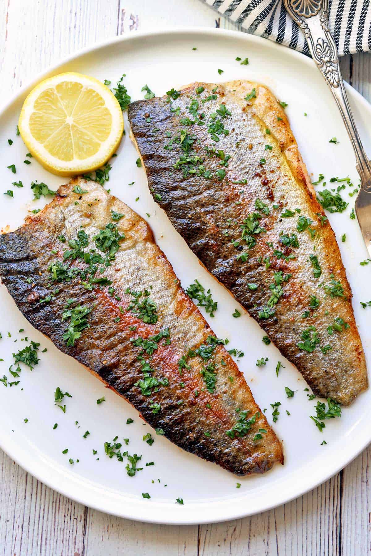 Rainbow trout fillets served on a white plate. 
