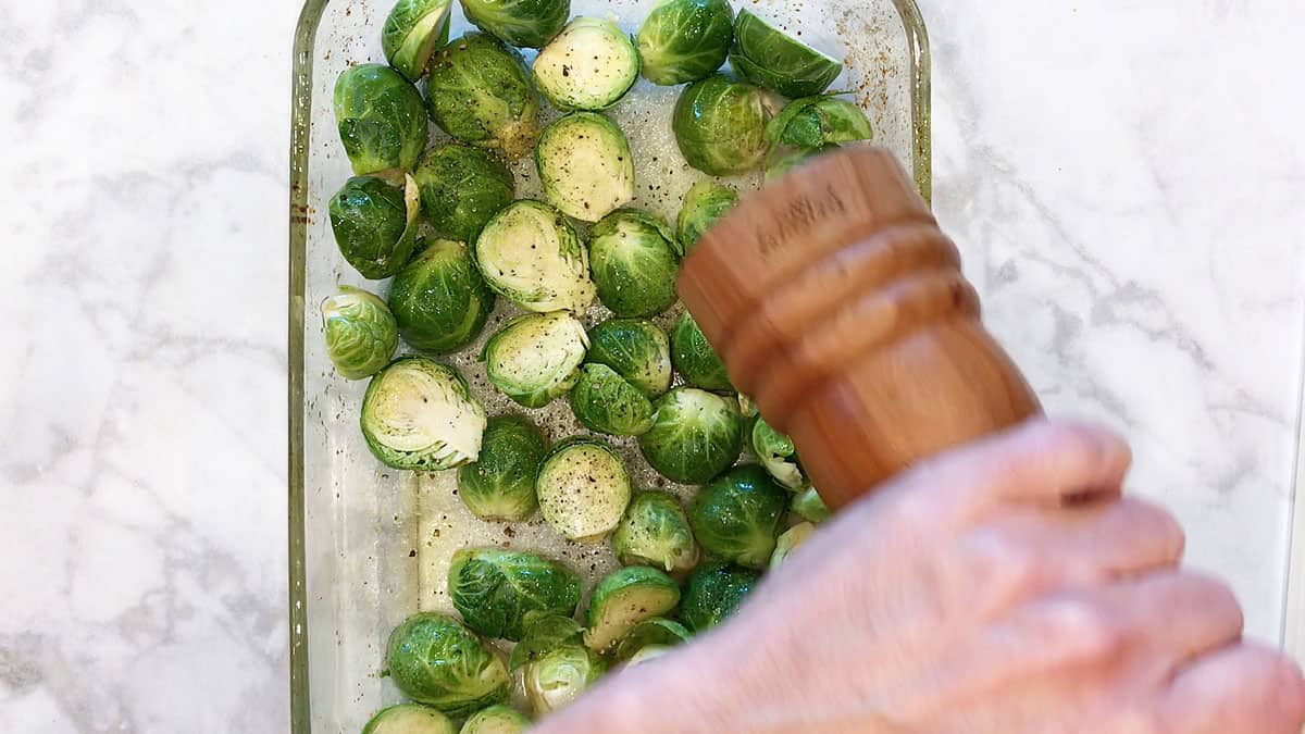 Seasoning Brussels sprouts with salt and pepper. 