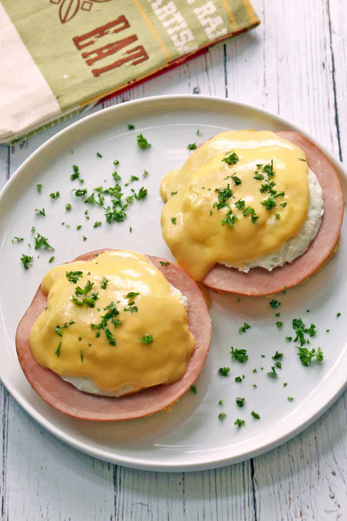 Keto eggs benedict served on a white plate, garnished with parsley. 