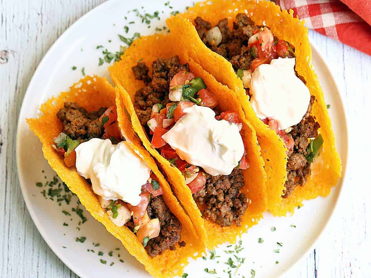 Keto tacos with a cheese shell, stuffed with ground beef, salsa, and sour cream. 