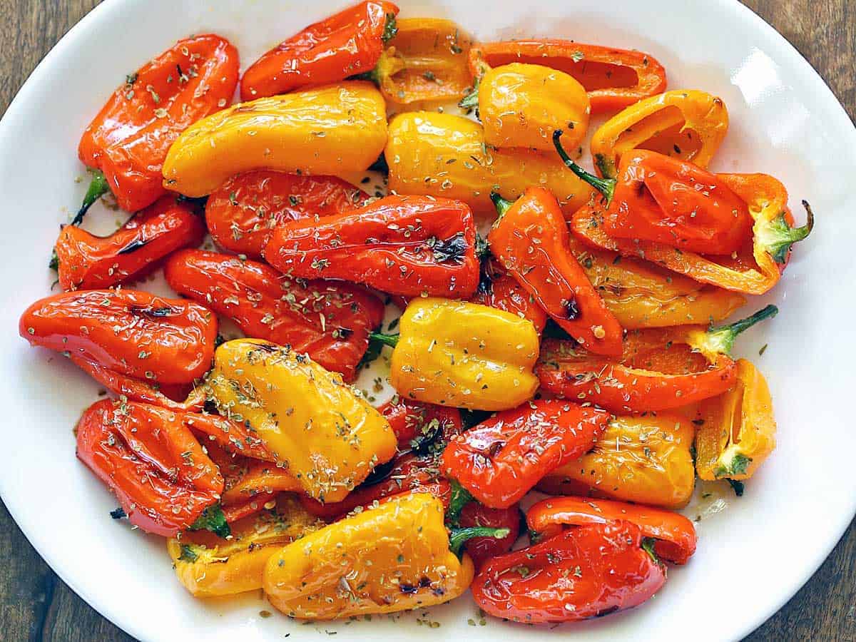 Roasted mini sweet peppers served on a white platter. 