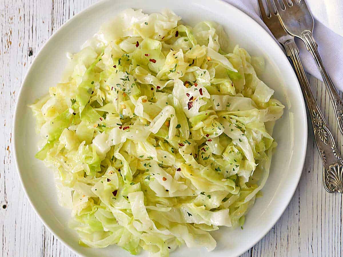 Steamed cabbage served on a white plate with forks. 