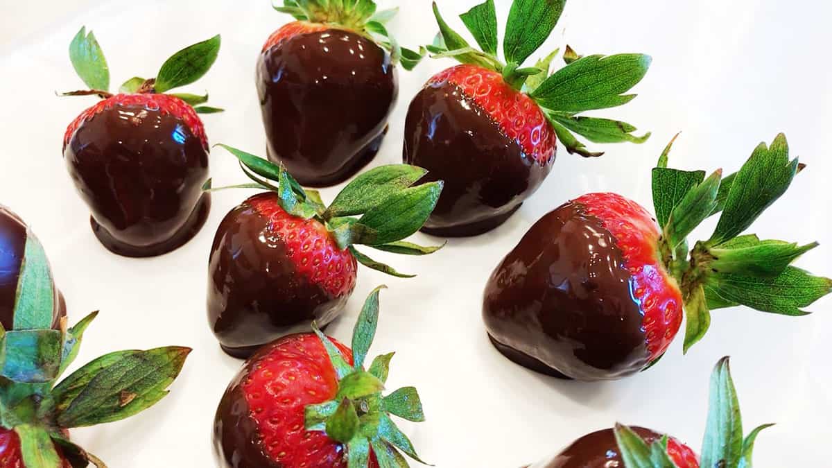 Chocolate-dipped strawberries arranged on a wax paper-lined plate. 