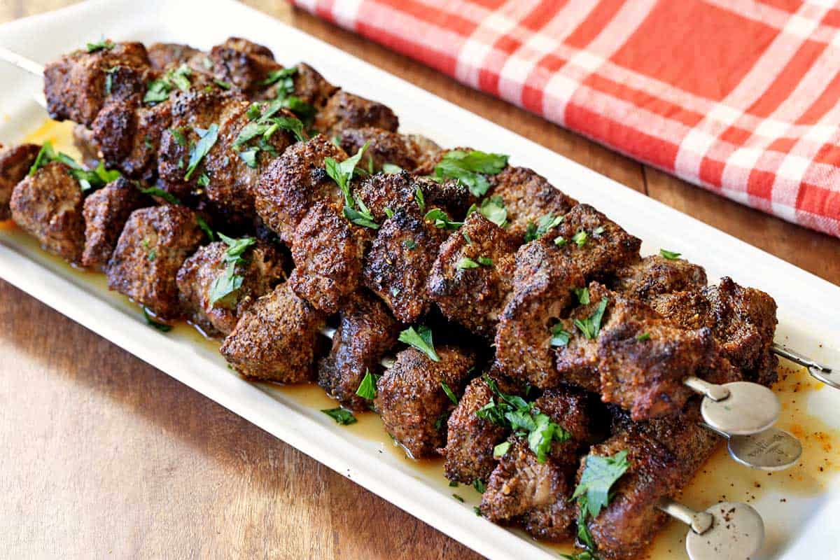 Beef kabobs served on a white tray. 