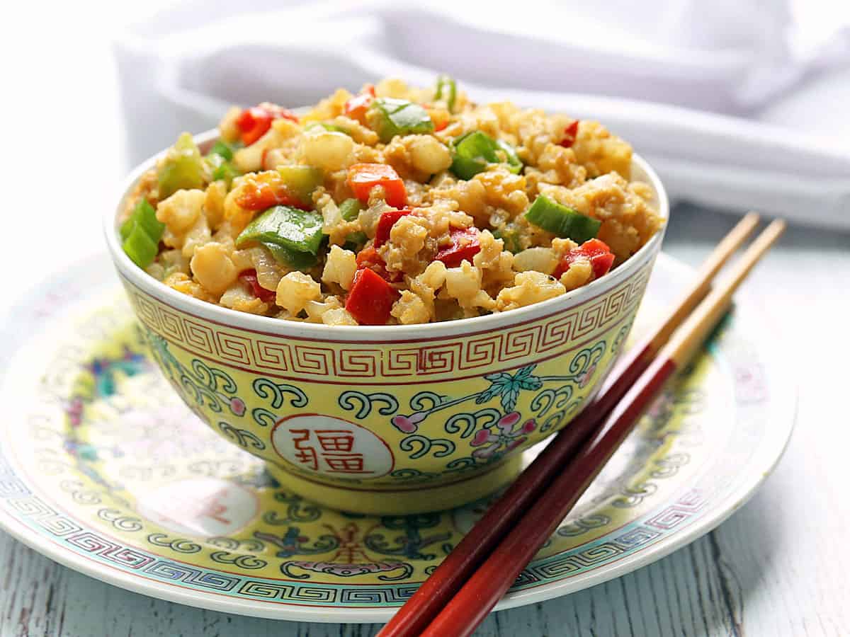 Cauliflower fried rice served in a bowl with chopsticks. 