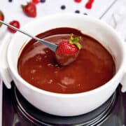 A strawberry is dipped into chocolate fondue.