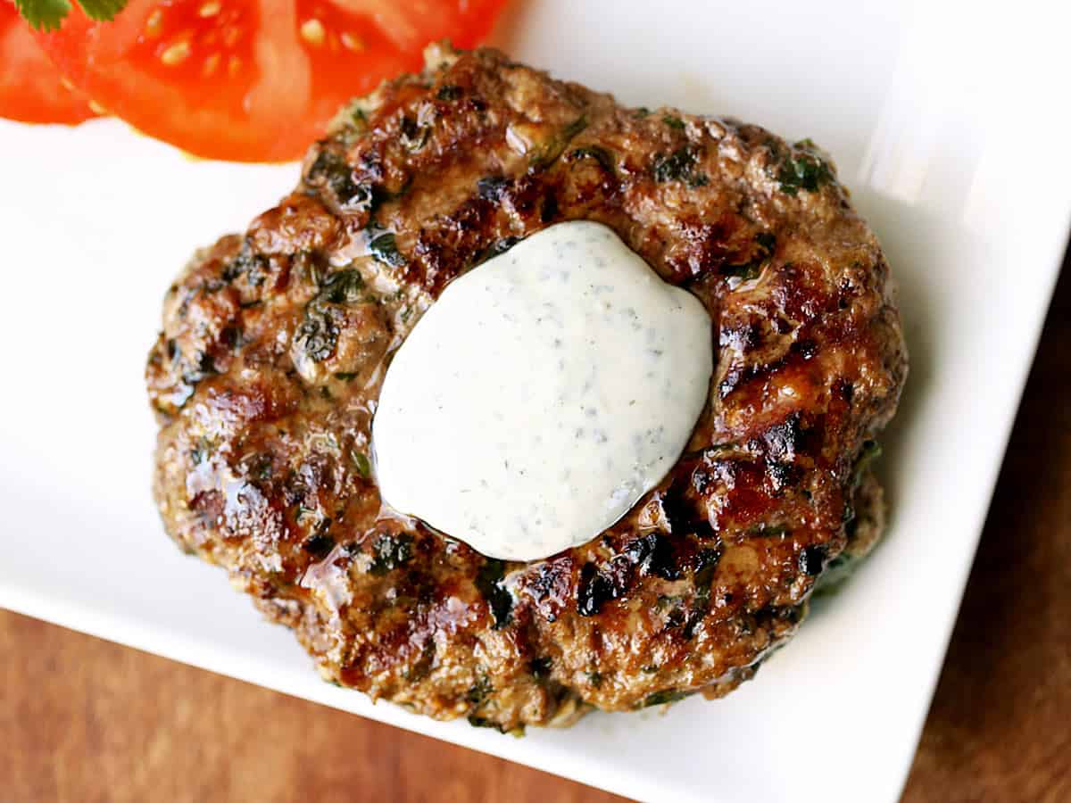 Lamb burgers topped with yogurt sauce and served with tomatoes. 