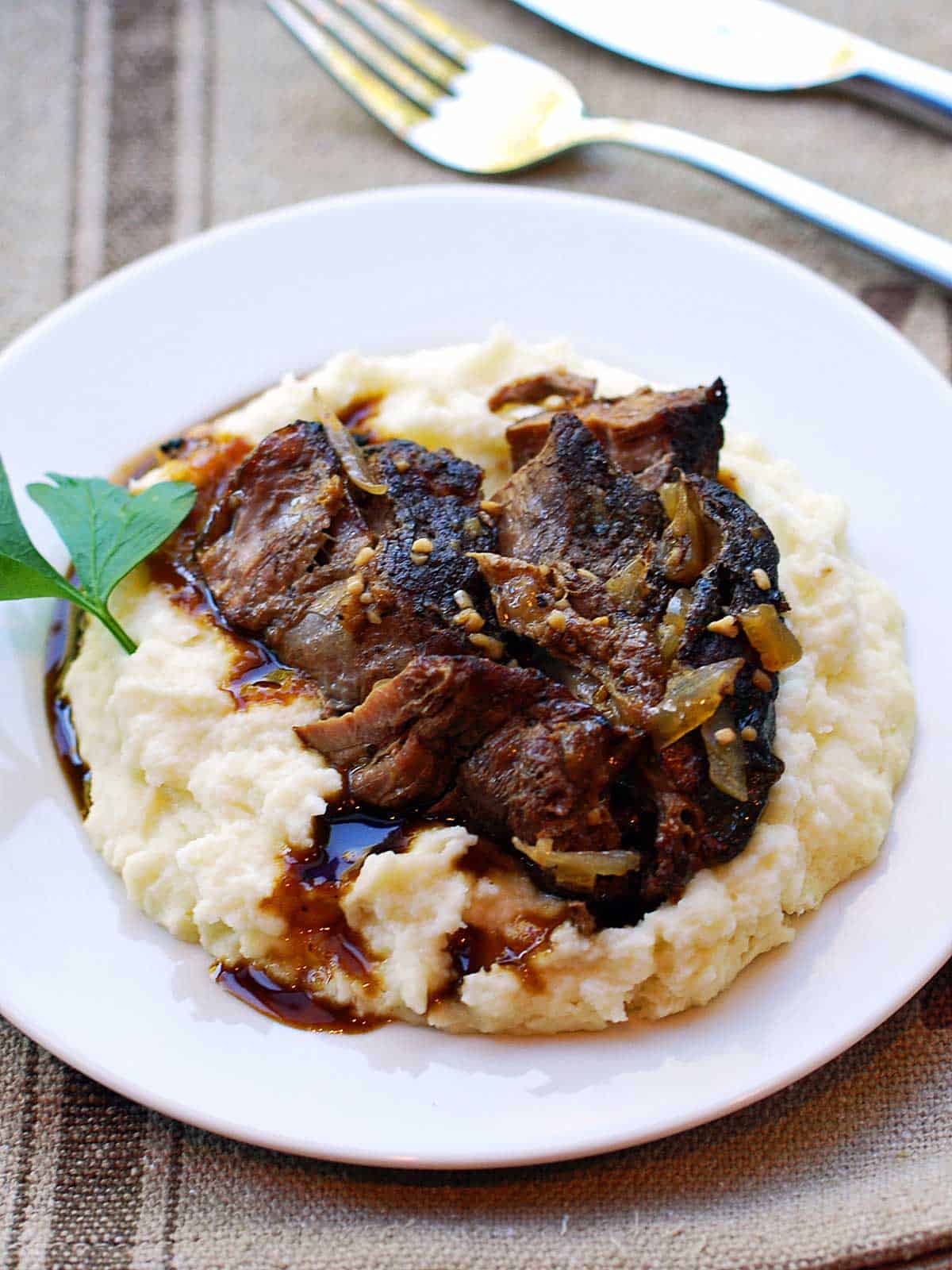Keto pot roast served on a bed of mashed cauliflower. 