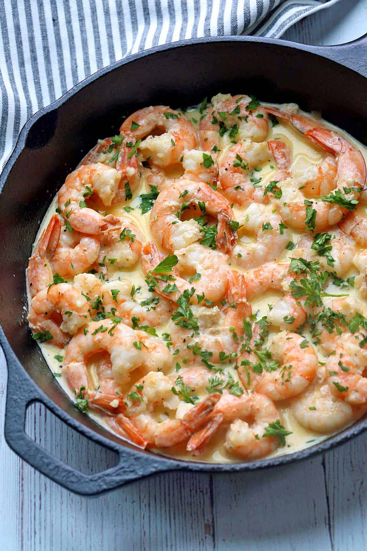 Shrimp in cream sauce served in a skillet and topped with parsley. 