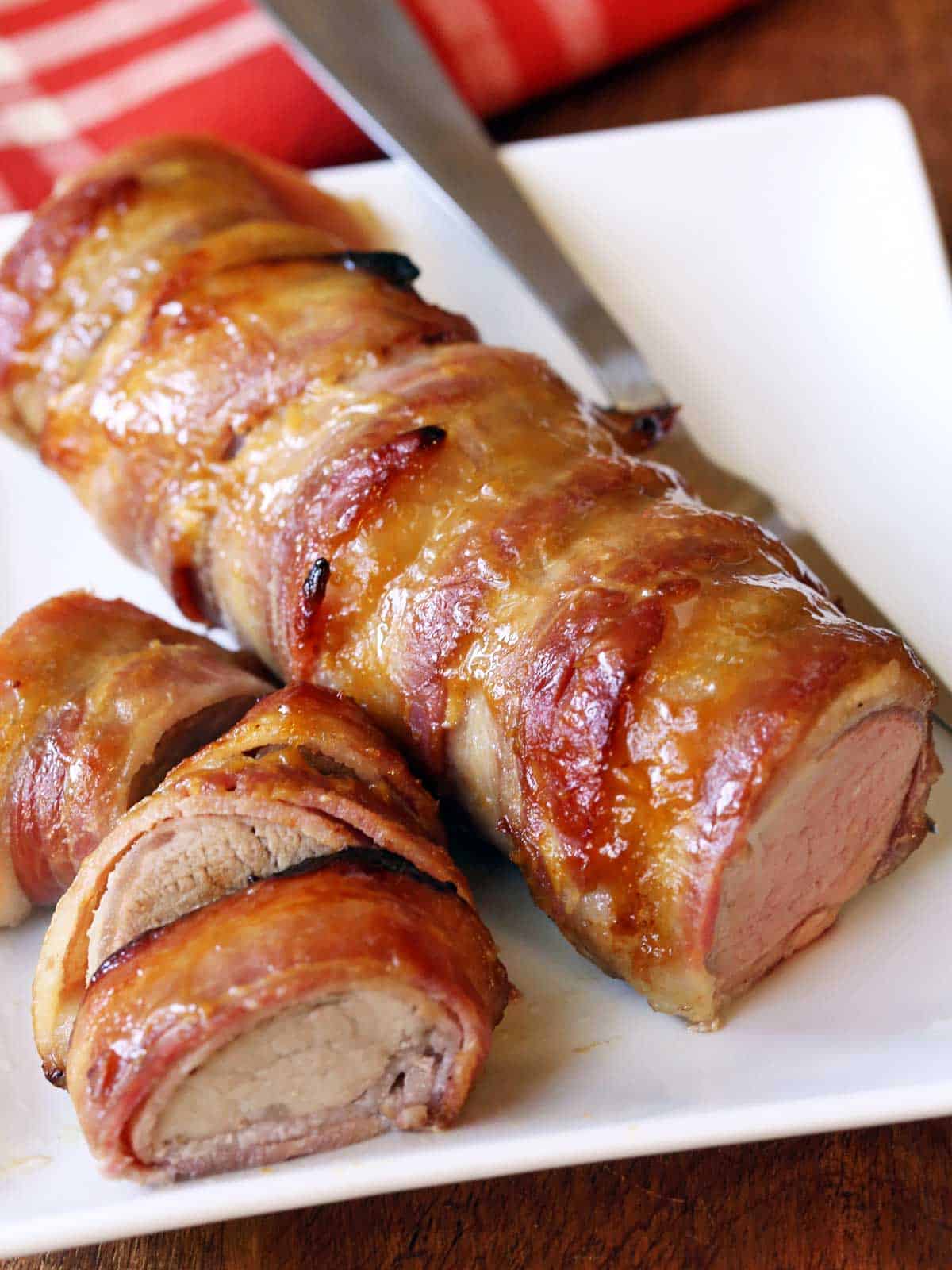 Bacon-wrapped pork tenderloin served with a serving fork. 