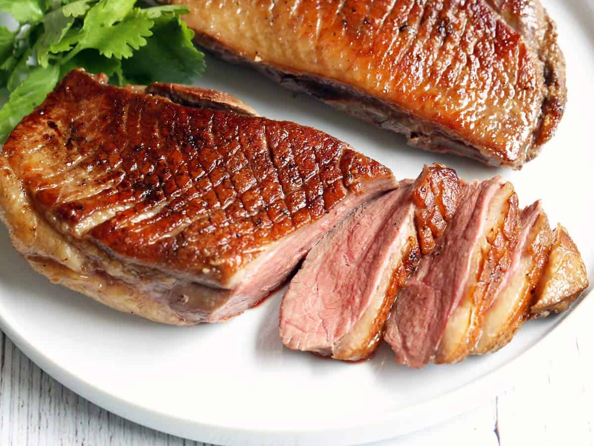 Duck breast, sliced and served on a white plate. 