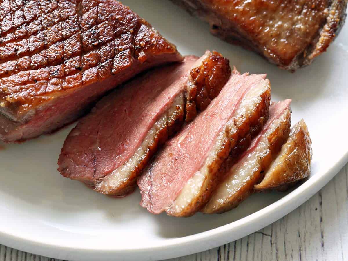 A close-up photo of a sliced duck breast. 
