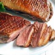 Duck breast, sliced, served on a white plate.