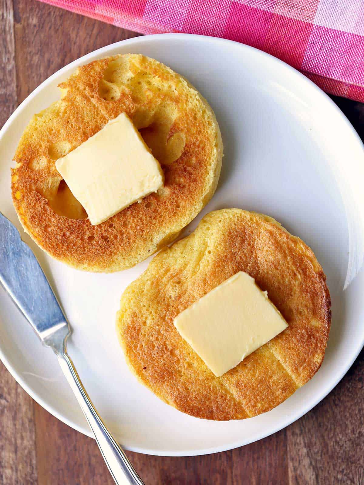 Keto English muffin served with butter and a butter knife. 