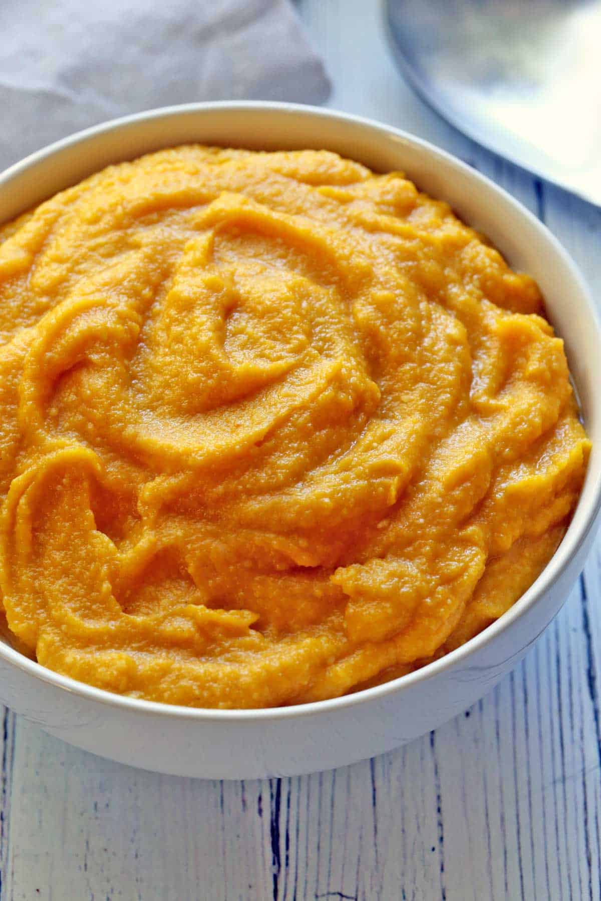 Mashed pumpkin served in a white bowl. 