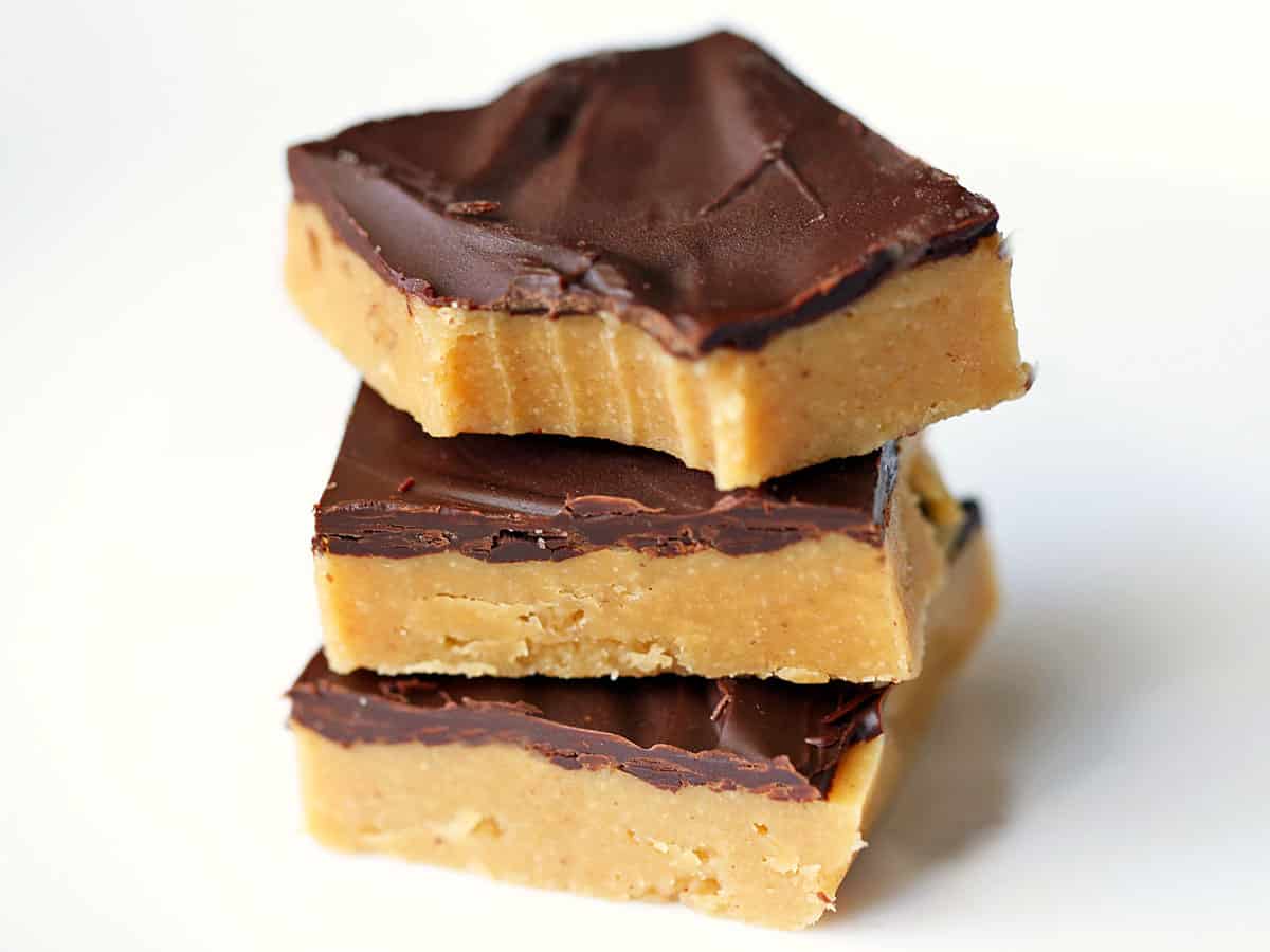 Three keto peanut butter bars stacked on a white plate. 