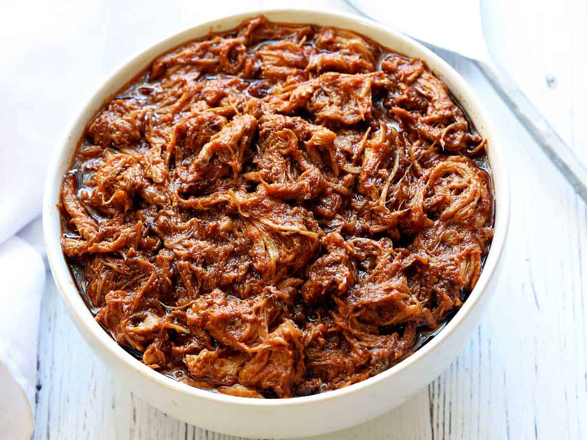 Slow cooked pulled pork served in a white bowl.  