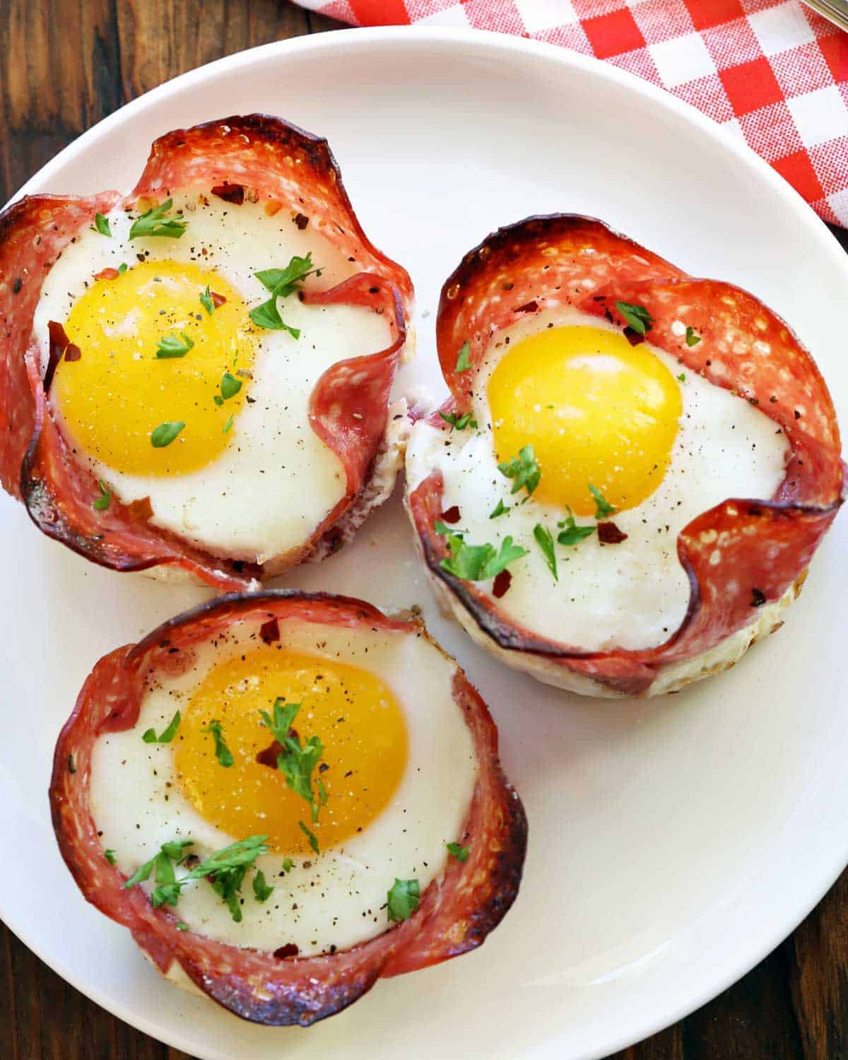 Salami and egg cups served on a white plate. 