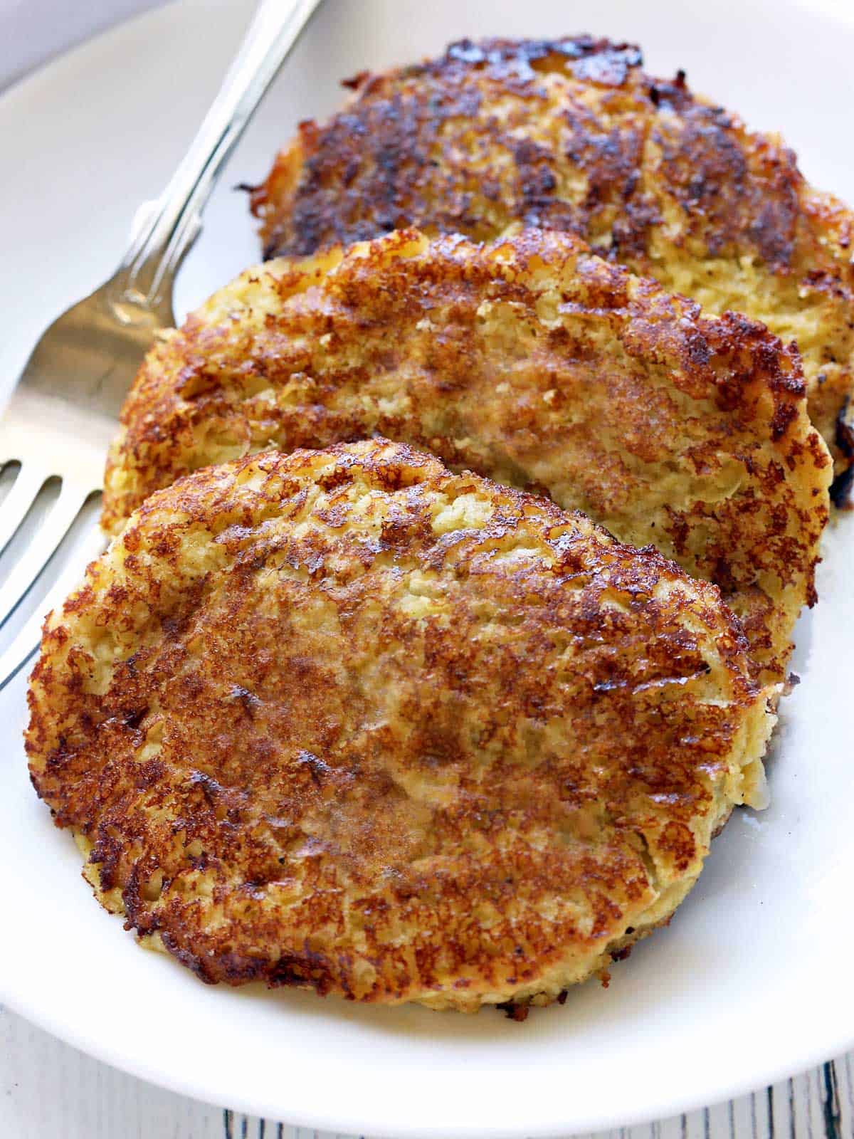 Three spaghetti squash fritters served on a white plate. 