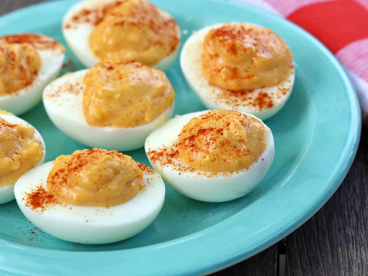 Spicy deviled eggs served on a turquoise plate.