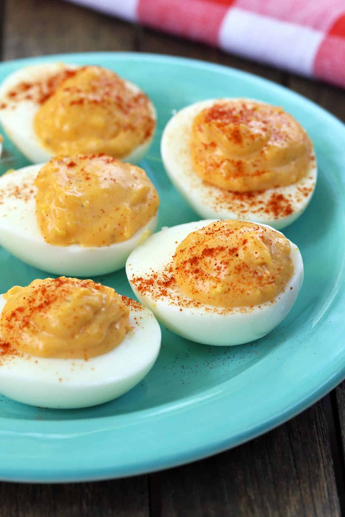 Spicy deviled eggs served on a turquoise plate. 