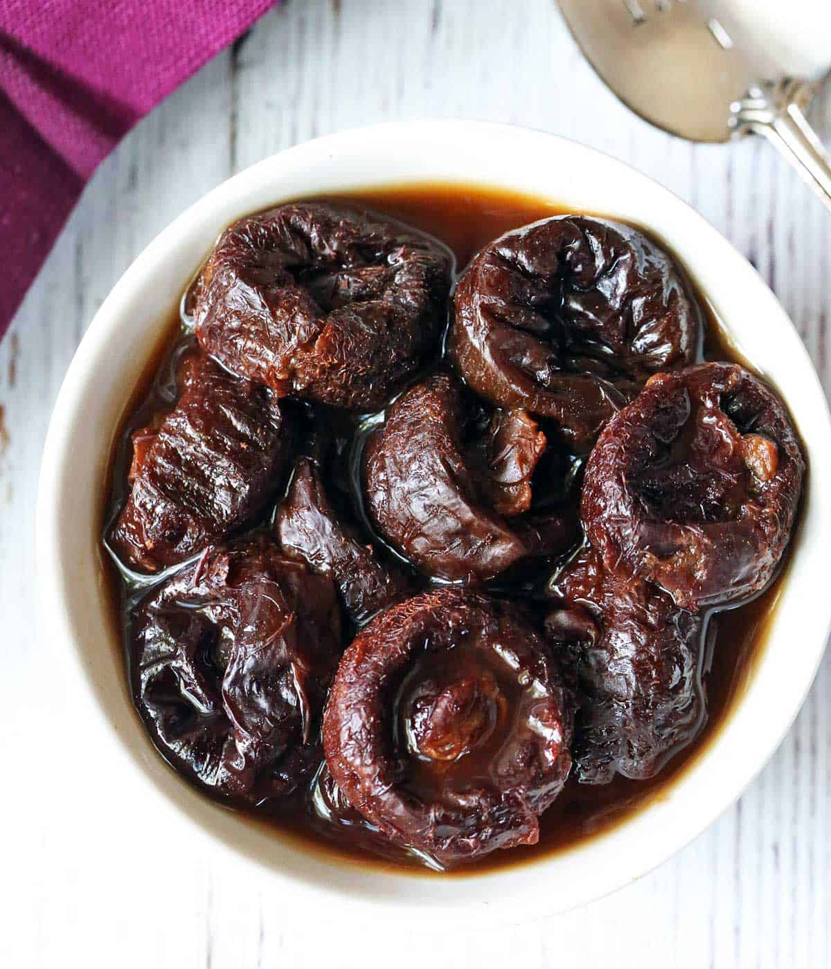 Stewed prunes served in a white bowl. 