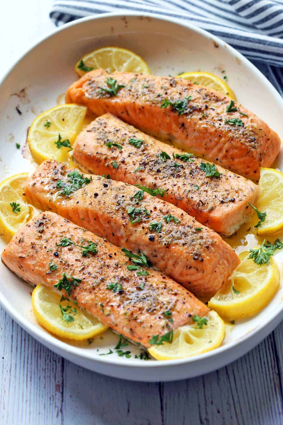 Four fillets of baked salmon served in a white dish. 