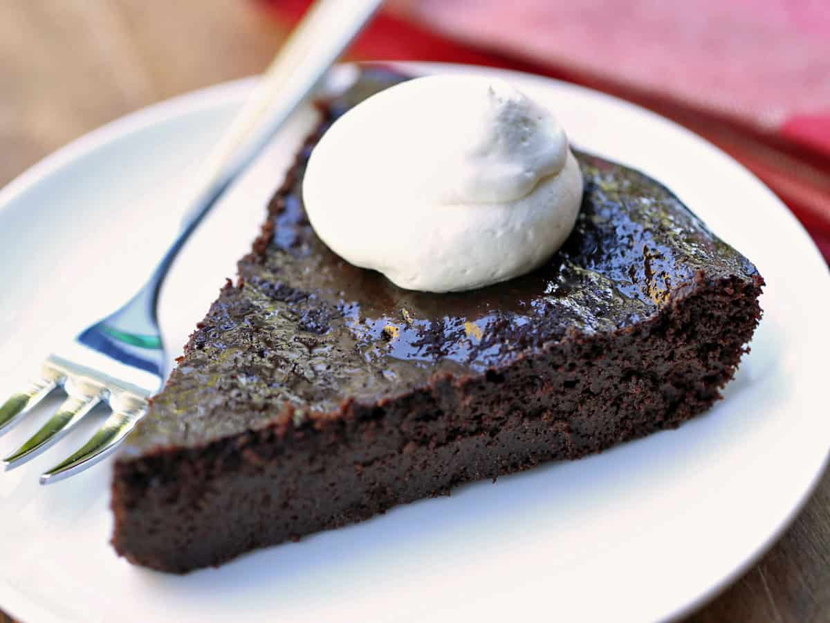 Una rebanada de pastel de chocolate ceto cubierto con crema batida. 