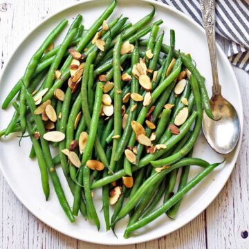 Green beans almondine served on a white plate.