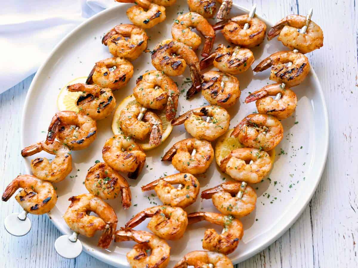 Grilled shrimp skewers on a white plate with a white napkin. 